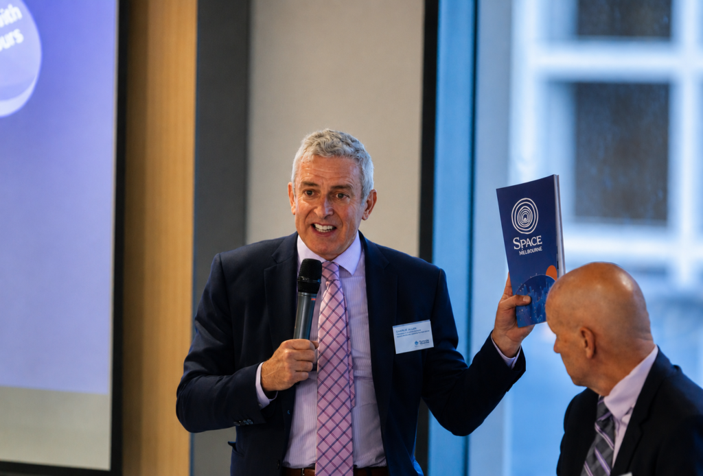 Charlie Allen presenting, holding a Space Melbourne brochure